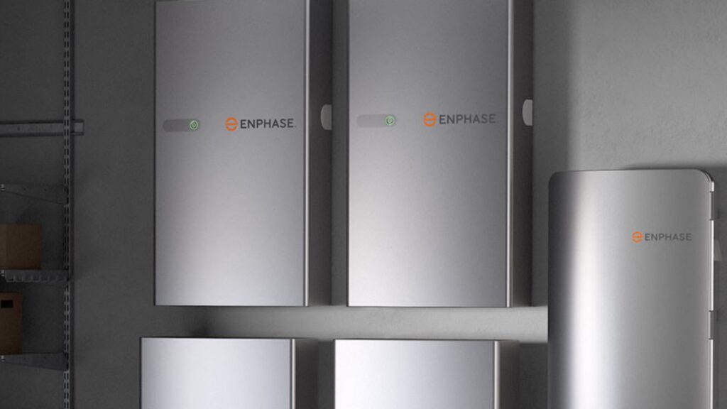 Multiple Enphase battery storage units are mounted on a wall in a garage or storage area.